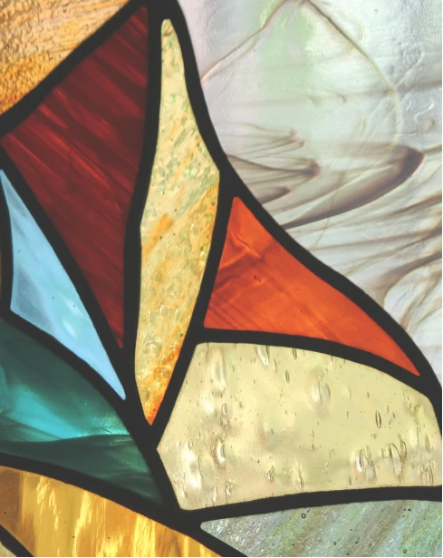 Close-up of colorful stained glass in red, teal, amber and gold